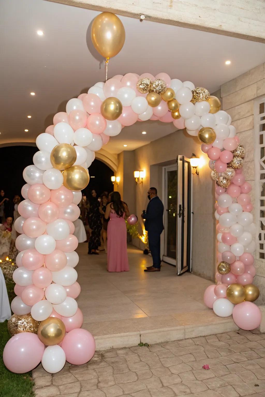 A dazzling balloon gateway in soft pink, brilliant gold, and elegant white extends a warm reception to all guests.