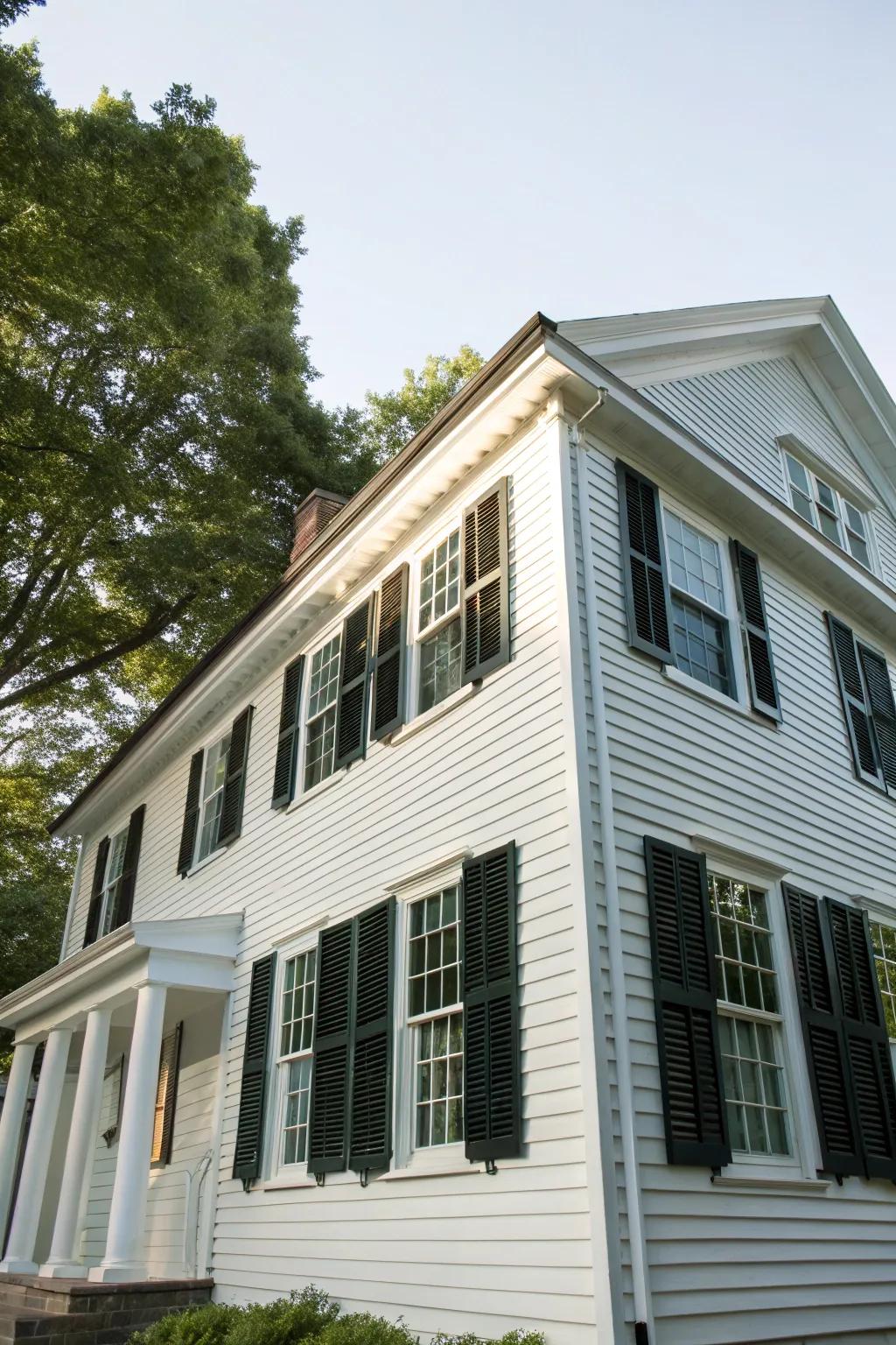 A colonial home showcasing traditional white vinyl siding and contrasting dark window panels.
