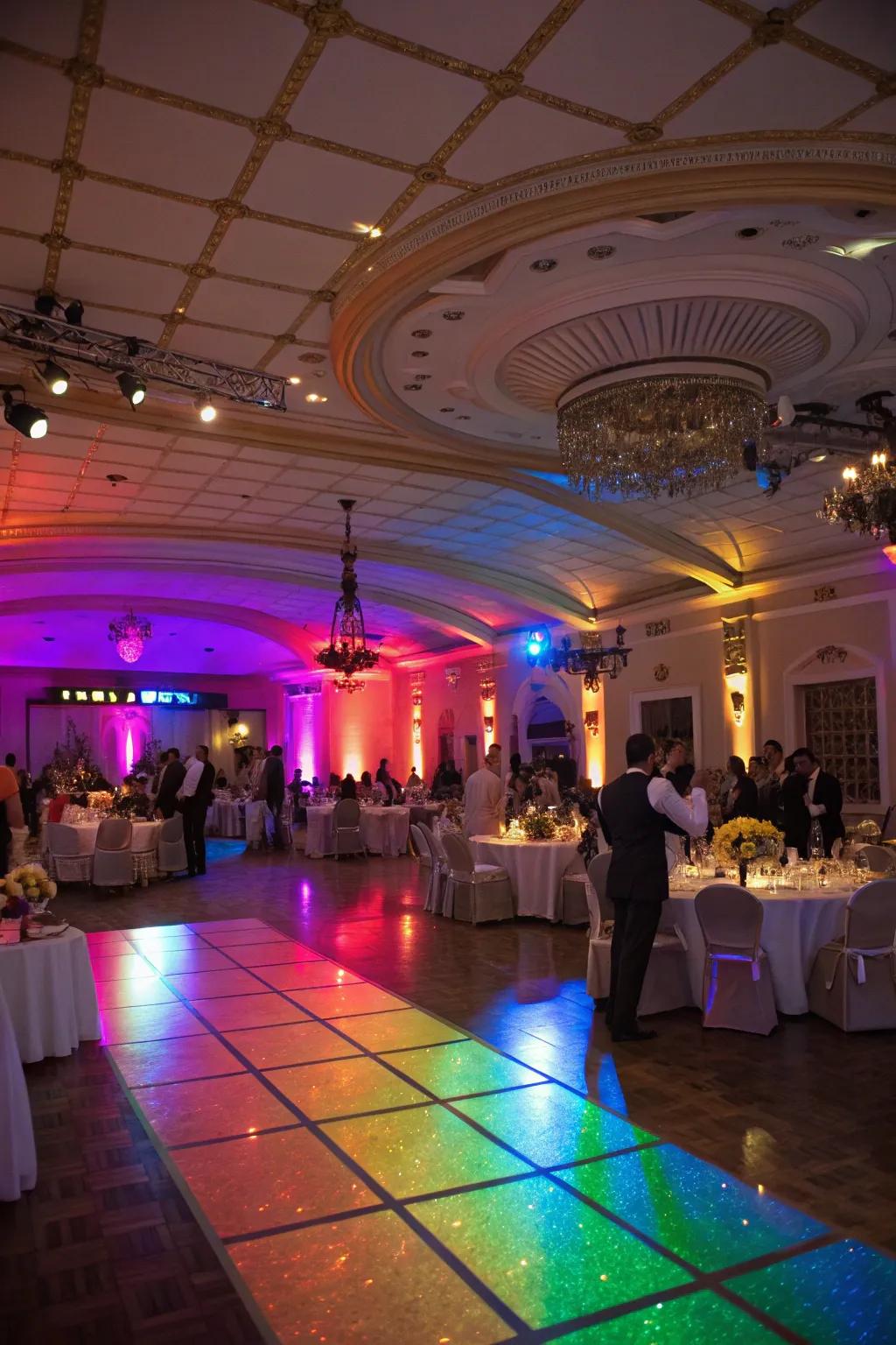 A wedding reception venue is bathed in vibrant rainbow lighting.