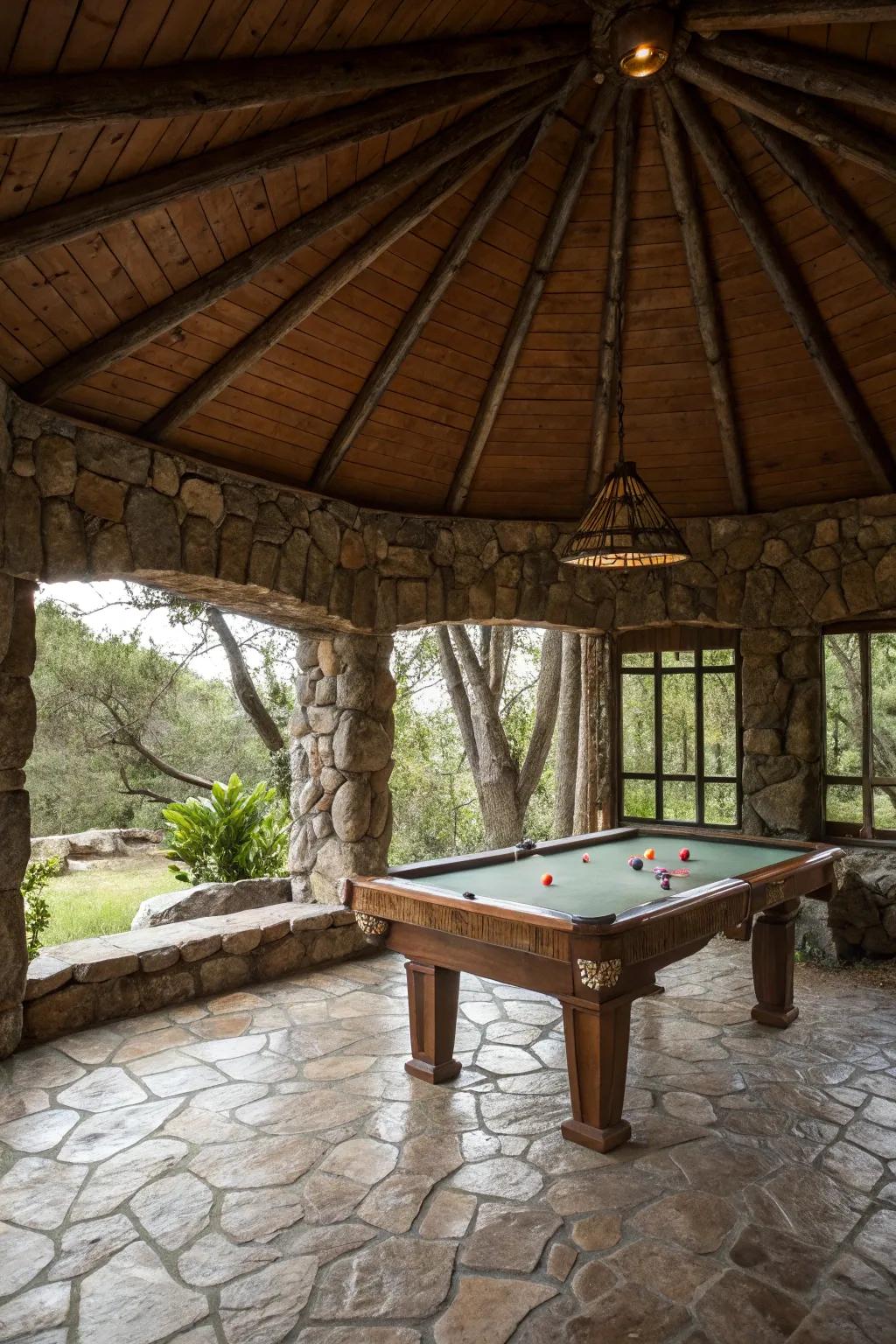A country stone gazebo that houses a pool table in a natural setting.