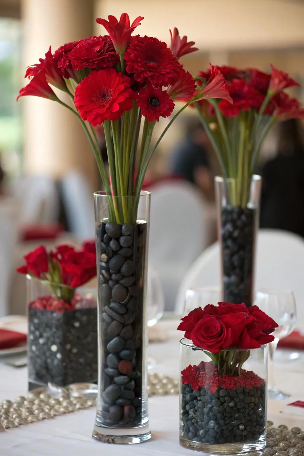 Vases of varied heights overflowing with scarlet flowers and obsidian stones for depth.