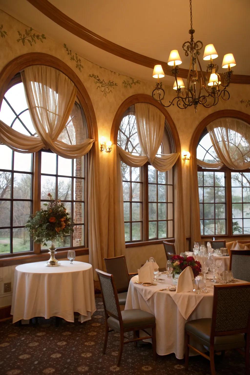 A romantic dining chamber features textile festoons on arched windows, producing a dreamy and inviting setting.