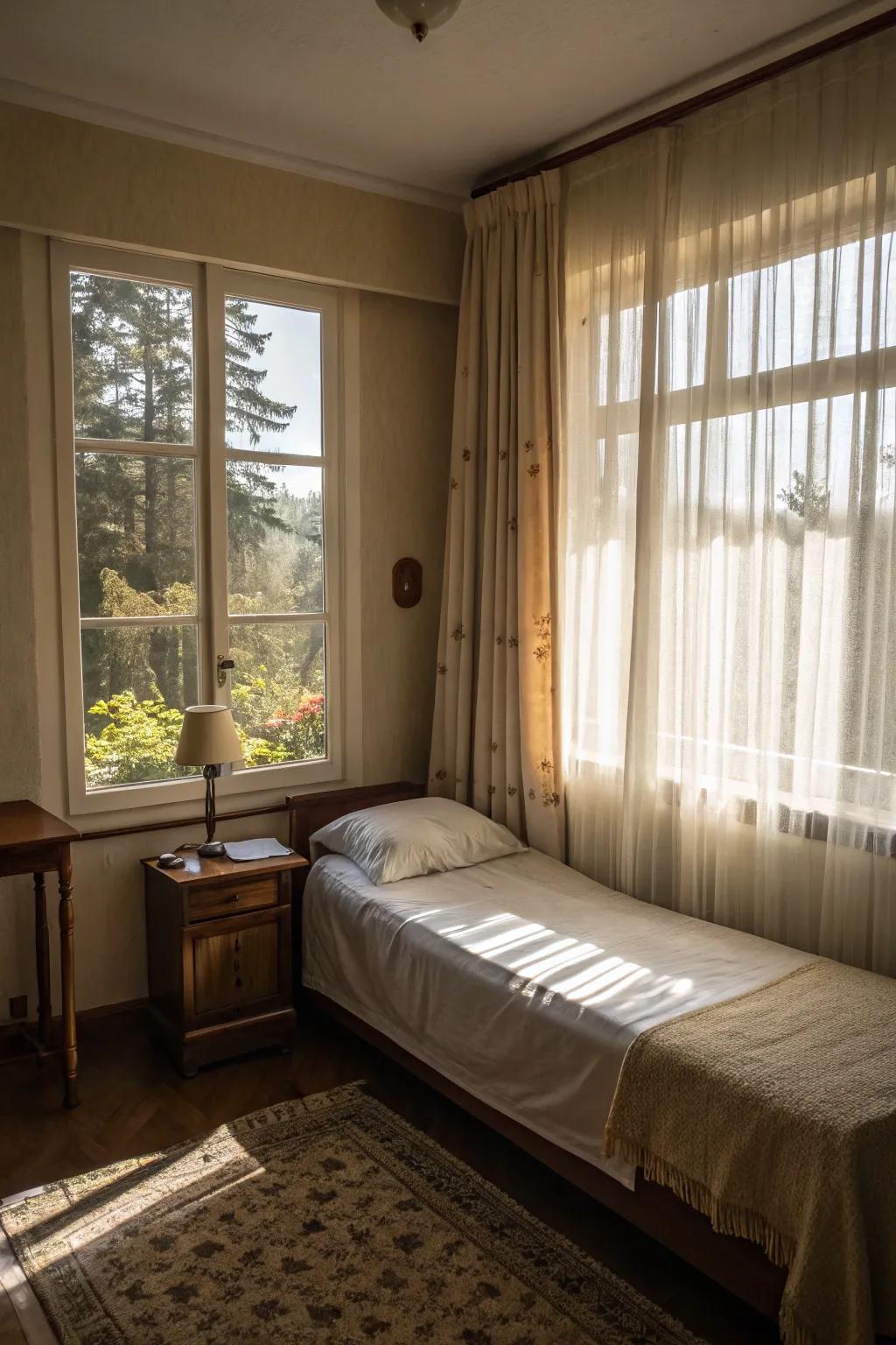 A compact bedroom filled with sunlight streaming through light, sheer curtains.