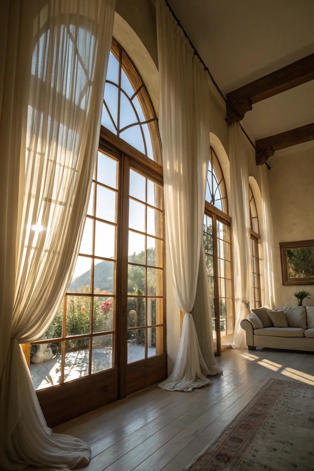 A sunlit space is adorned with clear veils on arched windows, conjuring a serene and spacious atmosphere.