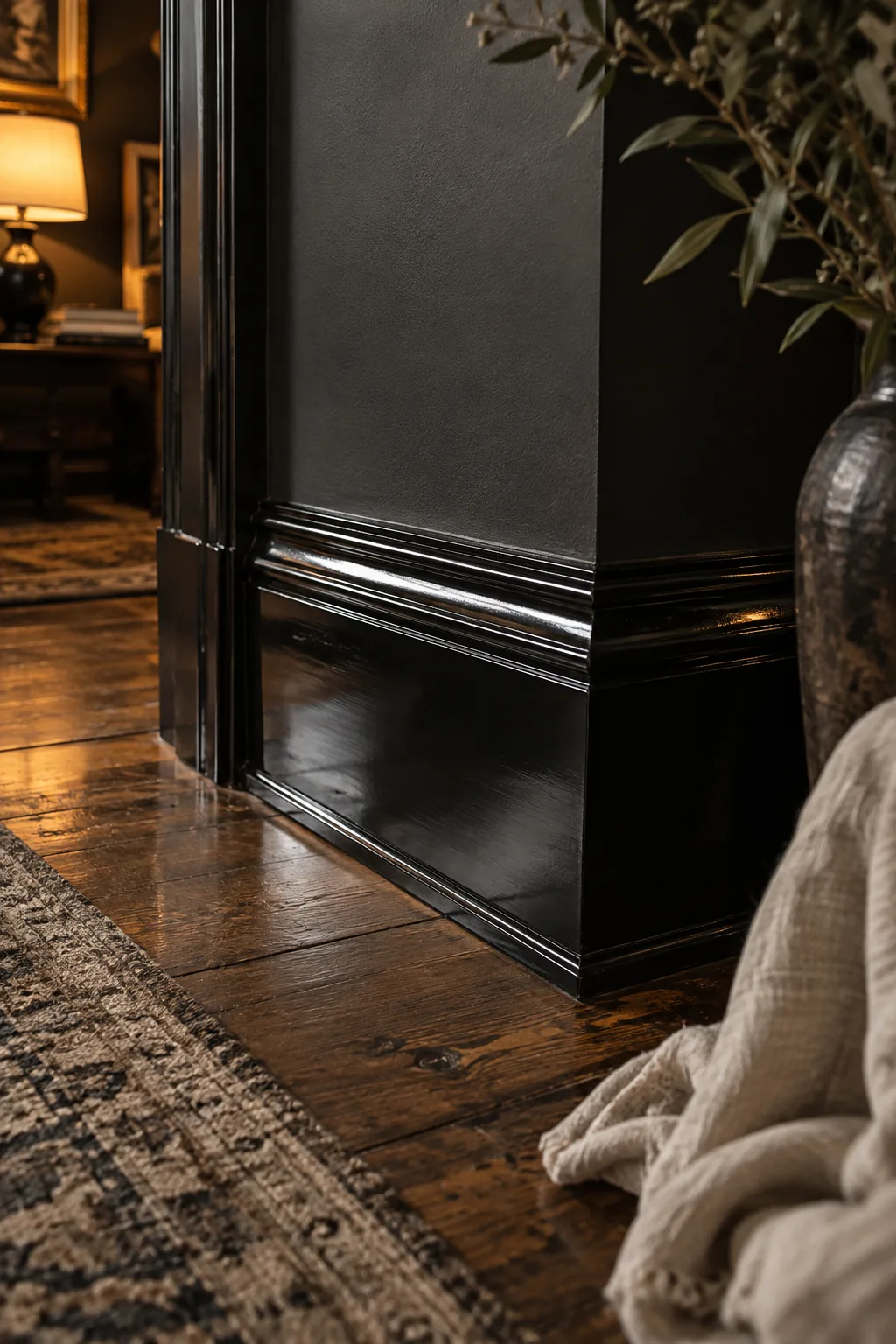 Glossy black baseboard trim against a dark matte wall.