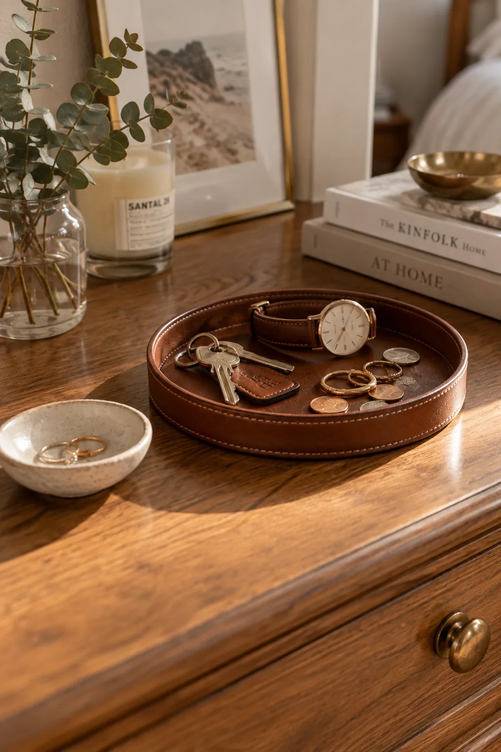 A small marble tray on a wooden dresser holding a watch and a bottle of room spray.