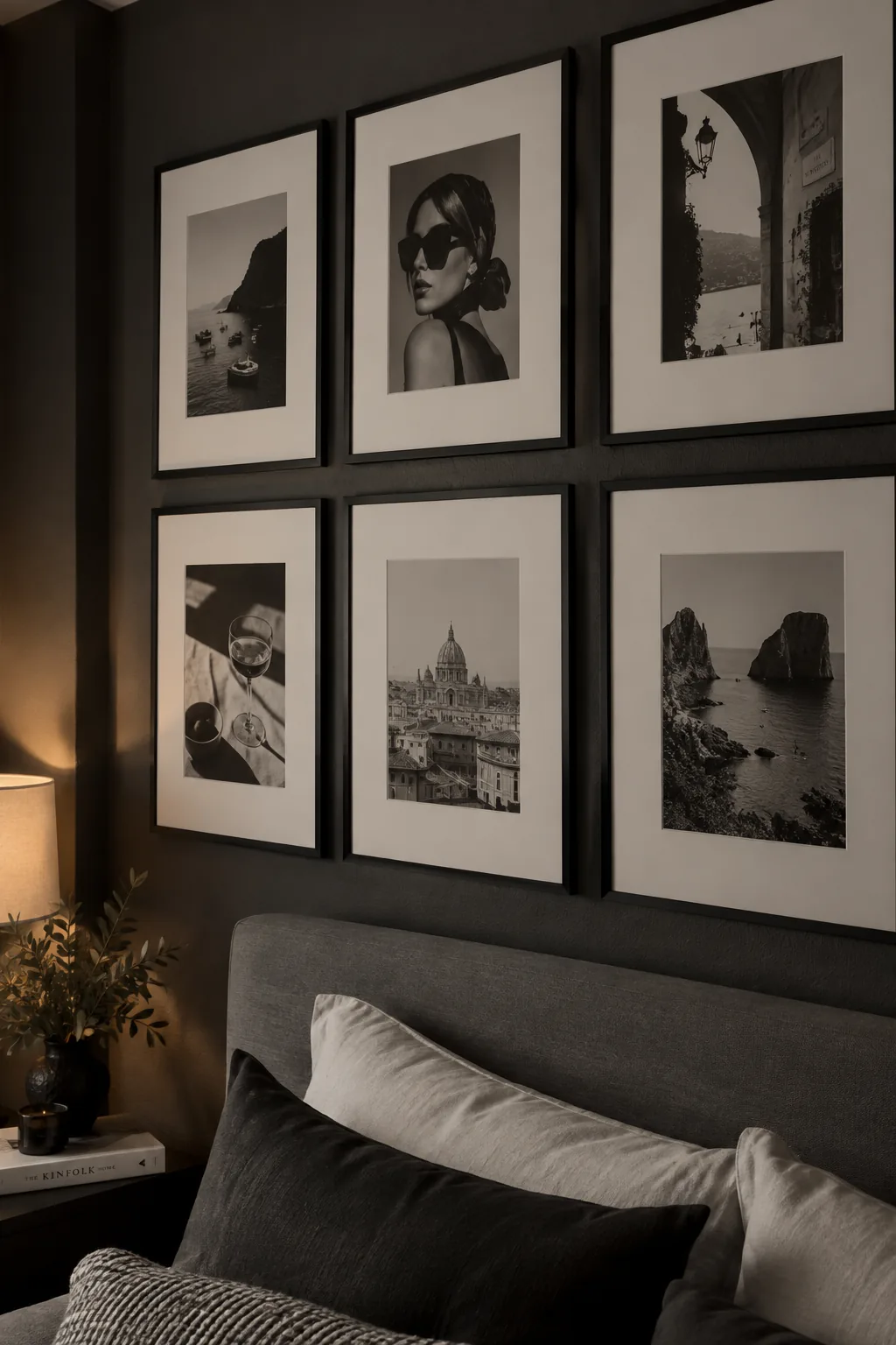 Gallery wall of black and white prints in black frames above a bed.