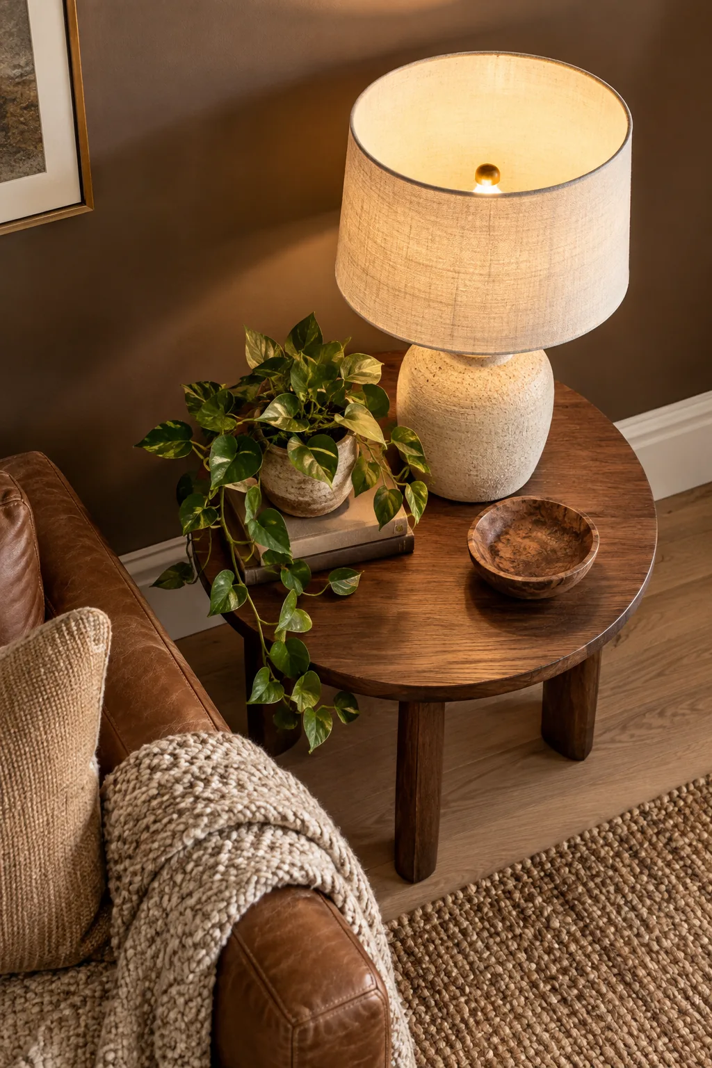 A linen table lamp casting a warm glow against a dark mocha wall.
