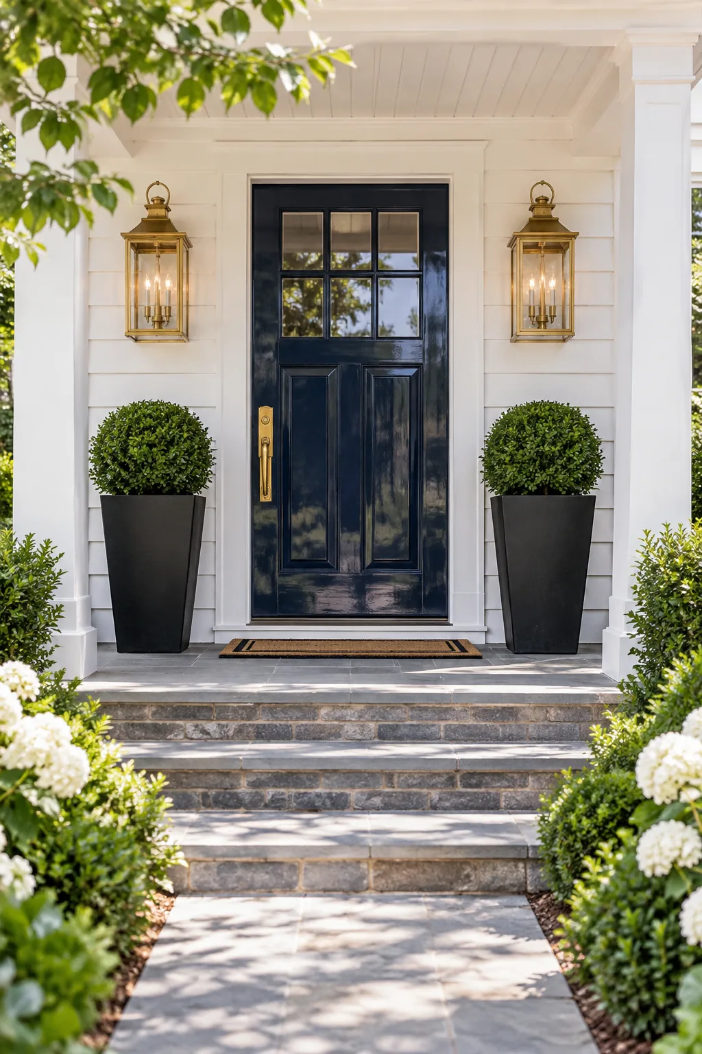 A symmetrical front porch viewed from the walkway, featuring a navy door and matching decor on both sides.