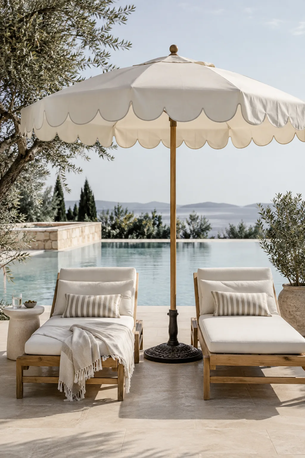 White scalloped edge patio umbrella shading two pool loungers