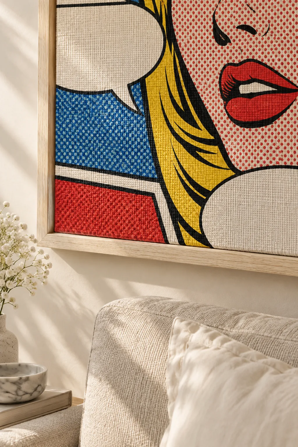Large comic strip painting hanging above a solid colored modern sofa in a bright living room.