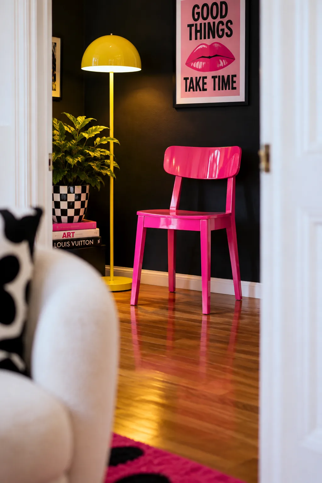 A traditional wooden chair painted in glossy hot pink sitting against a matte black wall.