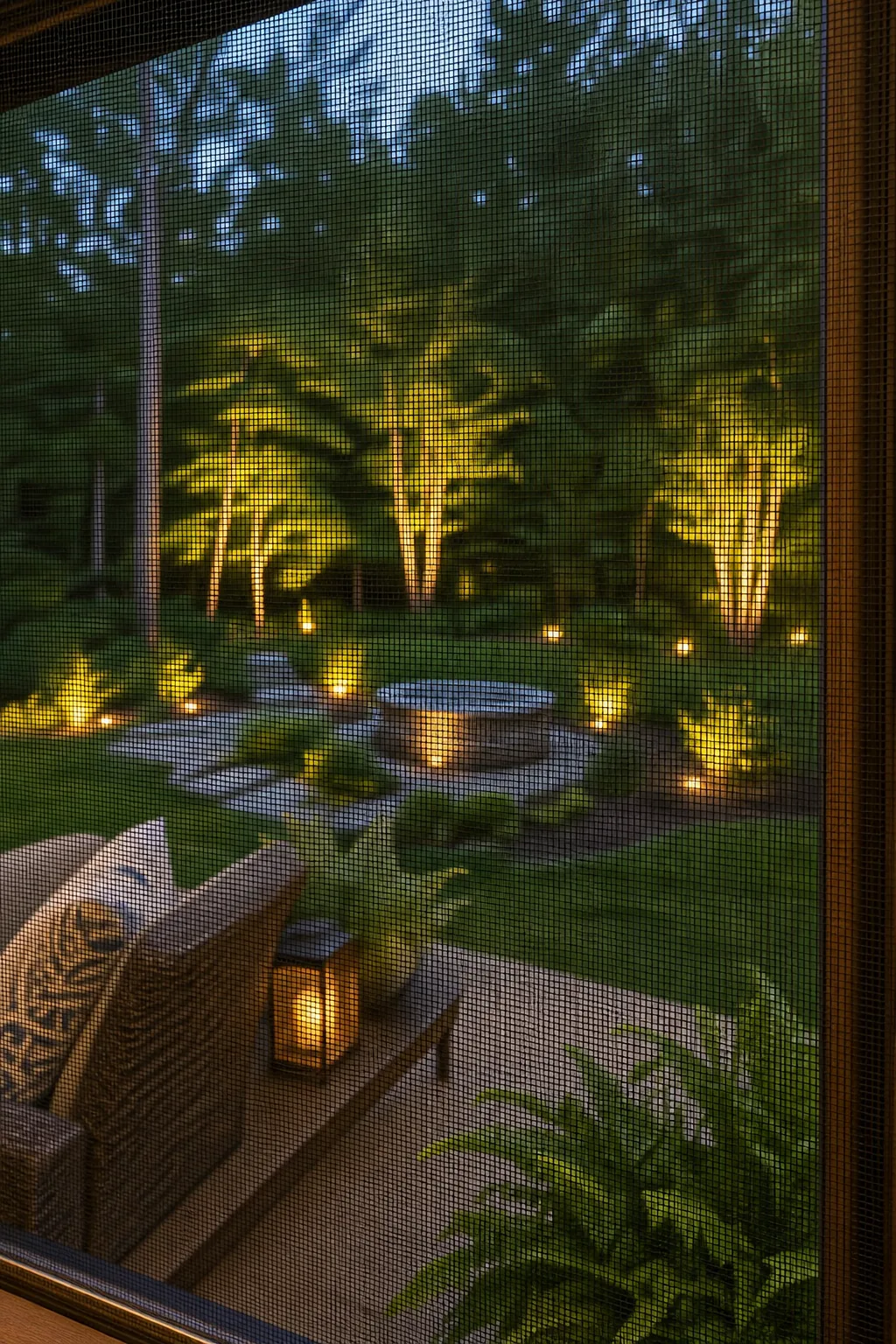 View looking through fine black screen mesh toward a green backyard.