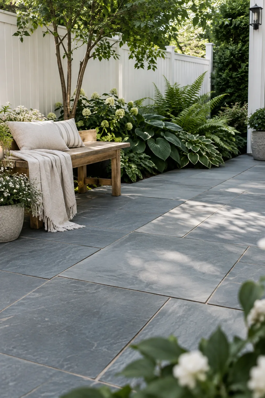 Large rectangular bluestone slabs laid as a patio next to garden beds