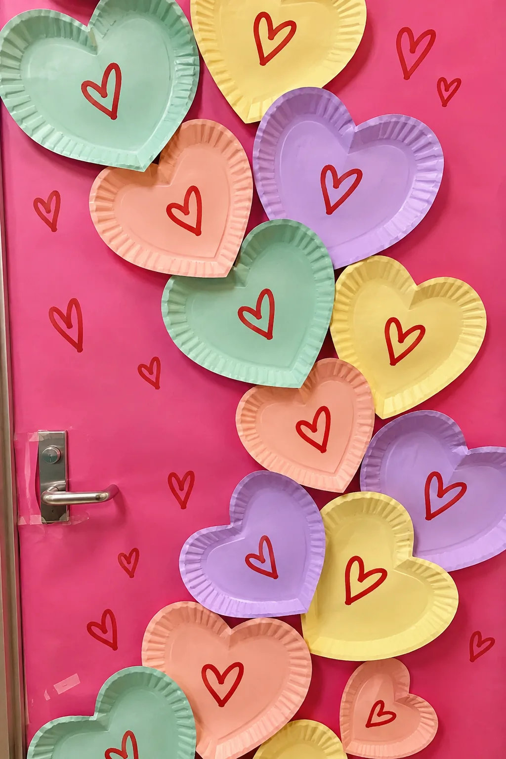 Pastel paper plates decorated like conversation hearts on a door