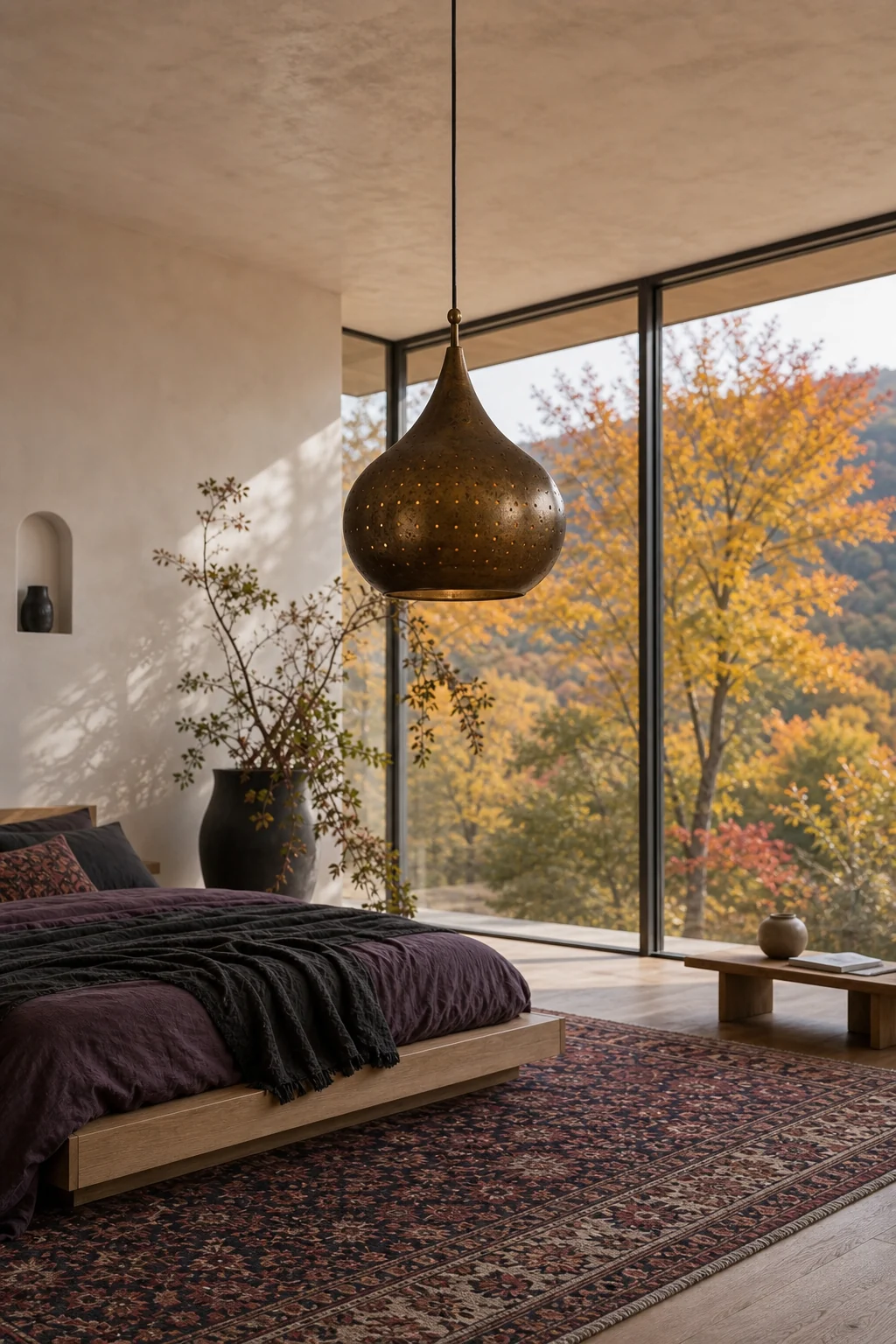Oxidized brass pendant light hanging in front of expansive unadorned windows and warm white plaster.