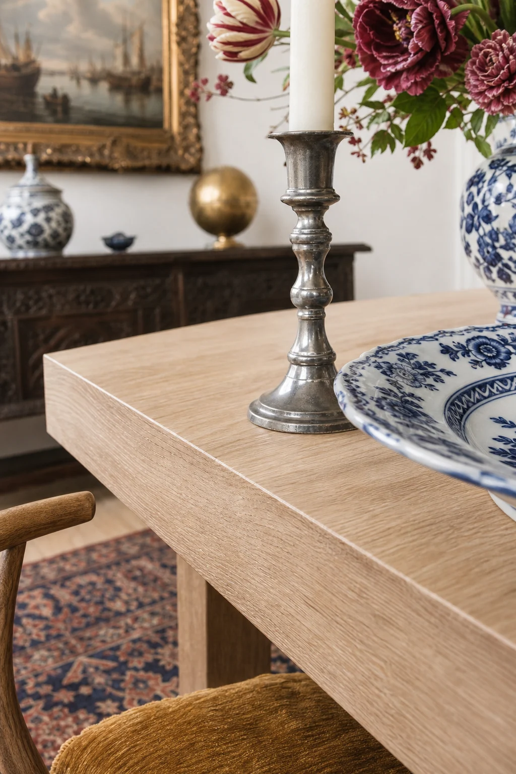Macro detail of a pale oak table edge meeting an antique pewter candlestick.